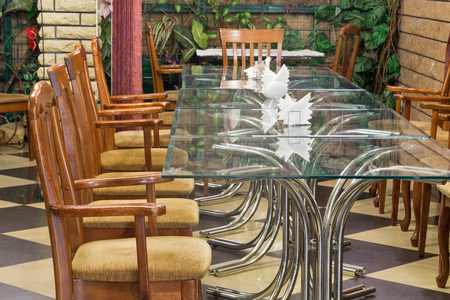 Interior of an old restaurant with old wooden chairs and glass tables.