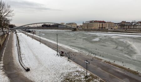 KRAKOW, POLAND - JANUARY 13, 2017: Winter cityscape with frozen Vistula river, moored pleasure craft ships, Kurland boulevard and Bernatka foot bike bridge. It is longest and largest river in Poland.のeditorial素材