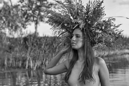 Beautiful caucasian young naked woman with wreath of flowers have fun in water. Ivan Kupala holiday celebration. Black and white.の写真素材