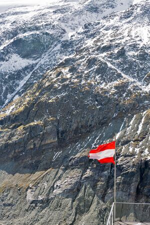 Austrian flag in front of mountain at Grossglockner High Alpine Road area in Austria.の写真素材