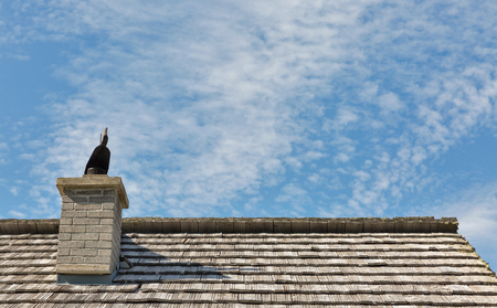 Old wooden lodge roof with chimney and blue sky in Alpine mountains, Austria.の写真素材