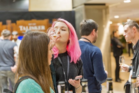 KIEV, UKRAINE - NOVEMBER 25, 2017: Unrecognized young woman tasting Single Malt Scotch Whisky at 3rd Ukrainian Whisky Dram Festival in Parkovy Exhibition Center.のeditorial素材