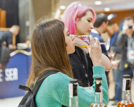 KIEV, UKRAINE - NOVEMBER 25, 2017: Unrecognized young woman tasting Single Malt Scotch Whisky at 3rd Ukrainian Whisky Dram Festival in Parkovy Exhibition Center.のeditorial素材