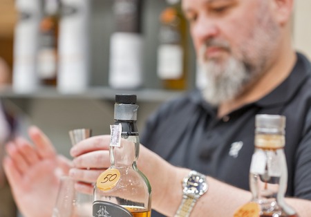 KIEV, UKRAINE - NOVEMBER 25, 2017: Unrecognized sommelier pours Single Malt Scotch Whisky into measuring cup at 3rd Ukrainian Whisky Dram Festival in Parkovy Exhibition Center.のeditorial素材