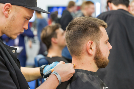 KIEV, UKRAINE - OCTOBER 07, 2017: Hairdresser makes hairstyle on Remington booth, personal care corporation, during CEE 2017, largest electronics trade show of Ukraine in ExpoPlaza Exhibition Center.のeditorial素材
