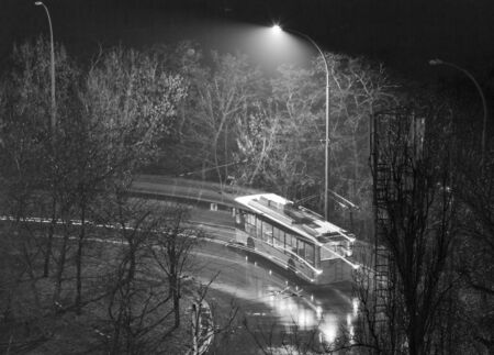 trolley bus on street at night in bad weather in black and whiteの写真素材