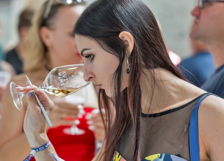 KIEV, UKRAINE - JUNE 2, 2018: Young woman tastes white wine at Kyiv Wine Festival. Big festival of wine and food was organized by Good Wine company, 77 winemakers from around the world took part there.のeditorial素材