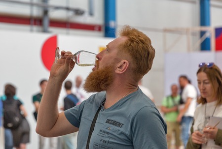 KIEV, UKRAINE - JUNE 02, 2018: Young redheaded man tastes white wine at Kyiv Wine Festival. 77 winemakers from around the world took part in the big festival organized by Good Wine company.のeditorial素材