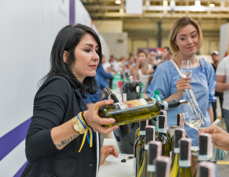 KIEV, UKRAINE - JUNE 02, 2018: Woman sommelier pours white wine at Kyiv Wine Festival booth. 77 winemakers from around the world took part big festival organized by Good Wine company.のeditorial素材
