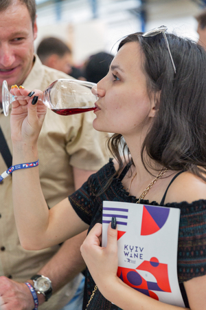 KIEV, UKRAINE - JUNE 2, 2018: Young beautiful woman tastes red wine at Kyiv Wine Festival. 77 winemakers from around the world took part in the big festival organized by Good Wine company.のeditorial素材