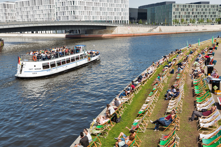 BERLIN, GERMANY - JULY 13, 2018: Captain Morgan touristic ship with passengers sailing along Spree river in front of popular Capital Beach club on a hot summer day in Mitte city district.のeditorial素材