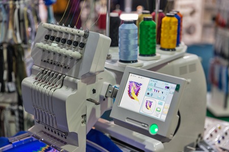 professional machine for applying embroidery on different tissues with colorful reels of threads...