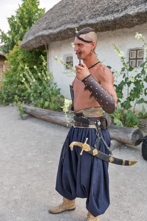 KHORTYTSIA, UKRAINE - JULY 03, 2018: Young Ukrainian Cossack portrait with forelock, tobacco pipe...