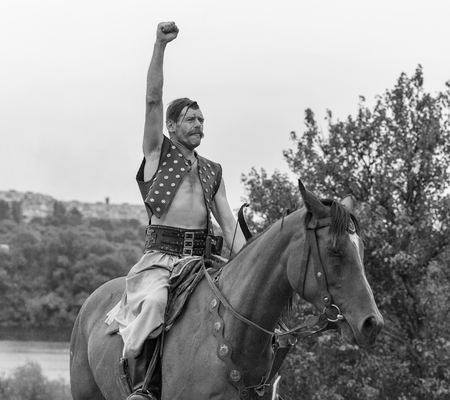 KHORTYTSIA, UKRAINE - JULY 03, 2018: Ukrainian Cossack horseman with raised fist in Zaporozhian Sich. It was inhabited by Cossacks who lived beyond the rapids of the Dnieper River in the 15th century.のeditorial素材