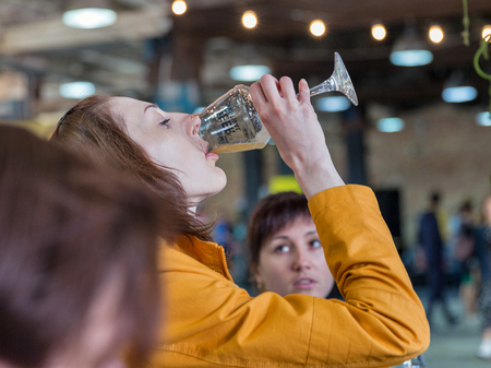 KYIV, UKRAINE - MAY 20, 2018: Young woman enjoy craft beer during Kyiv Beer Festival vol. 3 in Art Zavod Platforma. About 300 unique varieties of craft beer were presented here.のeditorial素材