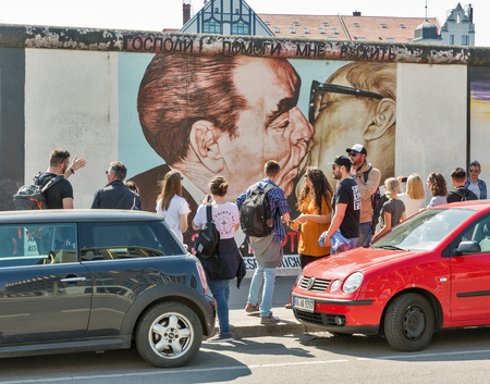 BERLIN, GERMANY - APRIL 19, 2019: People visit East Side Gallery with famous graffiti painting Fraternal Kiss Honecker - Brezhnev. Street art graffiti painting 'The Kiss' by Dmitri Vrubel.のeditorial素材