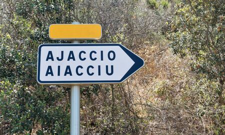 Ajaccio road sign. White arrow with destination city name, yellow copy space plate. Corsica island, France.の写真素材