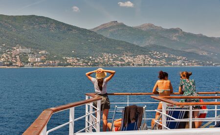 BASTIA, CORSICA, FRANCE - JULY 23, 2019: Passengers travel on the deck of Moby Vincent ferry passenger ship, cityscape in the background. Moby is an Italian shipping company that operates ferries.のeditorial素材