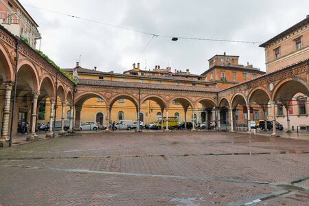 BOLOGNA, ITALY - JULY 10, 2019: People walk along ancient square in front of Basilica di Santa Maria dei Servi under the rain. It was founded in 1346 and was designed by Andrea da Faenza.のeditorial素材