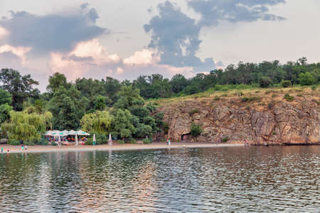 KHORTYTSIA, UKRAINE - JUNE 28, 2019: People visit ZAlK sandy beach of Khortytsia island at sunset. Khortytsia is the largest island on the River Dnieper.のeditorial素材
