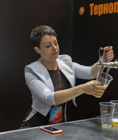 KYIV, UKRAINE - MAY 19,2016: Woman presenter pours beer at Aqua Therm exhibition of energy efficient heating, ventilation, air conditioning, water supply, renewable energy, plumbing, swimming poolsのeditorial素材