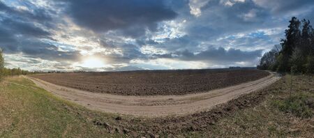 Rural sunset summer dramatic sky landscape panorama with cultivated field and dirty road in Central Ukraine.の写真素材