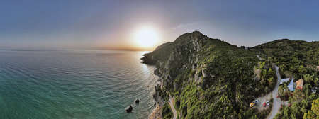 Aerial drone video over sunset Western Corfu coast panorama with Mirtiotissa beach, Greece.の写真素材