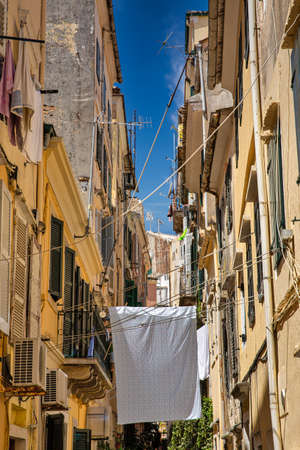 The washed laundry is dried on the clothesline in narrow streets of Kerkyra, Island of Corfu, Greece.の写真素材