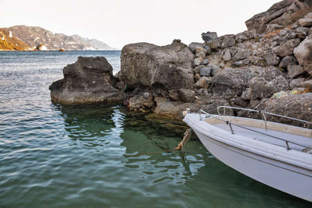 Small rowboat moored by the stones on the coast of Glyfada, Corfu, Greece.の写真素材