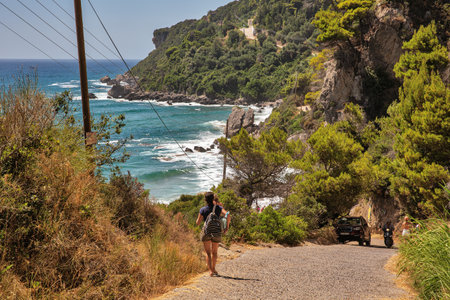 Glyfada, Corfu, Greece - August 06, 2021: People visit famous Mirtiotissa beach. It is a sandy naturist beach surrounded by rocks.のeditorial素材