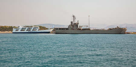 Kerkyra, Corfu, Greece - August 10, 2021: Hellenic Navy military tank landing ship L177 Rodos and Kerkyra Lines Menekratis ferry ship moored in Kerkyra port.のeditorial素材