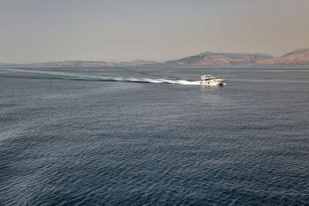 Seascape with speed motor boat sails in the distance off the coast of Greece