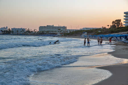 Ayia Napa, Cyprus - May 22, 2021: People have fun at summer sunset famous Limanaki Beach. Ayia Napa is a tourist resort at the far eastern end of the southern coast of Cyprus.のeditorial素材