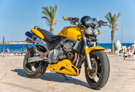 modern yellow sport motorbike closeup outdoors overlooking the sea in the background