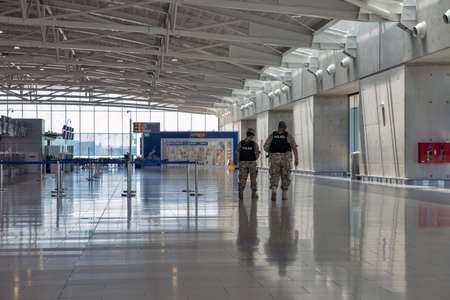 Larnaca, Cyprus - May 31, 2021: Police officers walk along check in flight registration counters in Glafcos Clerides Larnaca international airport. Larnaca is the third-largest city in the country.のeditorial素材