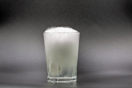 Dissolving instant effervescent tablets in a glass of water closeup on black