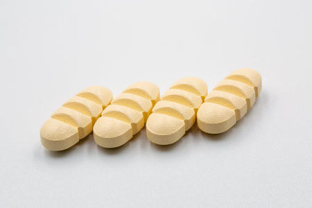 Yellow oblong tablets with dividing strips for dividing into four parts closeup on white.の写真素材