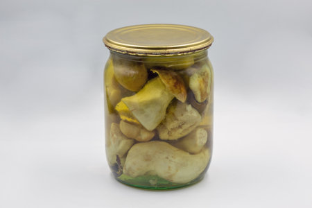 Glass jar of homemade marinated porcini mushrooms closeup on white.の写真素材