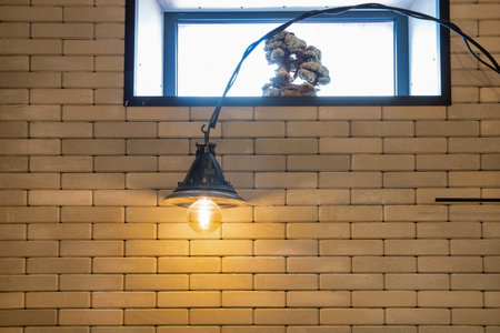 Loft industrial minimalist style electric lamp against window and brick wall indoorの写真素材