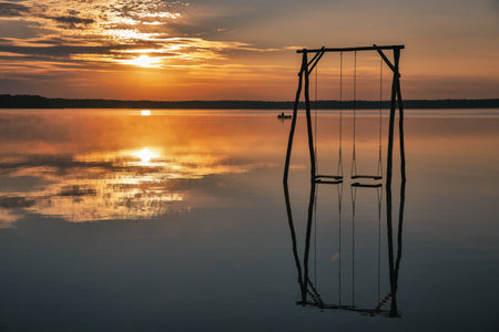 Panoramic view over romantic sunrise White Lake with wooden swing in Rivne region, Ukraine.