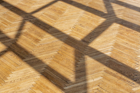 Abstract background with straight shadows from a window frame on old wooden parquet closeup.の写真素材
