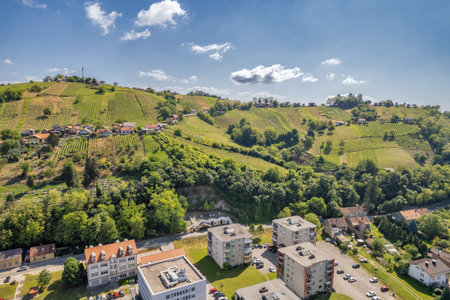 Aerial view of traditional Slovenian village nestled in rolling vineyard hills with terraced wine slopes, residential buildings and lush green countryside landscape. Lindava, Slovenia.の写真素材