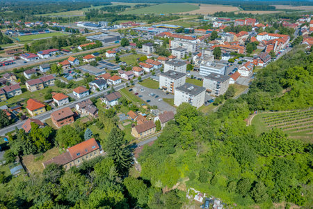 Aerial drone view of Lendava, Slovenia, showing a mix of residential buildings, apartment blocks, and green areas on the edge of the vineyards under a sunny summer sky.の写真素材