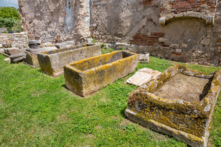 Ancient Roman archaeological site in Porec, Croatia showing excavated stone foundations, scattered ruins and artifacts on green grass with medieval buildings in background.の写真素材
