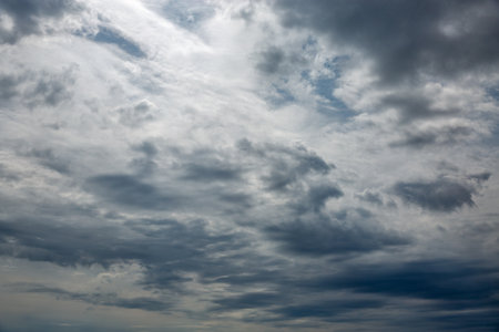 Dynamic cloudscape with swirling grey and white storm clouds creating dramatic patterns across...