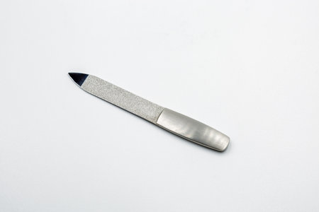 Silver metal nail file with diamond coated abrasive surface and smooth metallic handle closeup on...