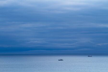 blue stormy sea with fishing boatsの写真素材