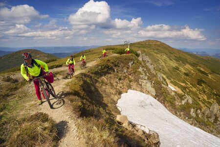 Montenegrin Mountains rocks and snow Spring, extreme climber climbs the steep cliff with the flag of Ukraine and mountain bike on the background of dawn. Far below the pine forest and bushのeditorial素材
