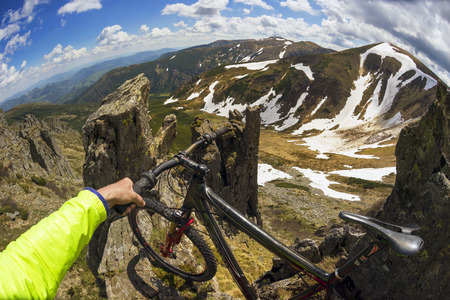 Ukraine, Verkhovyna, 29 June 2016: Montenegro ridge of rock and snow Spring, extreme climber climbs the steep cliff tract Gudgeon and mountain bike on the background of dawn.のeditorial素材