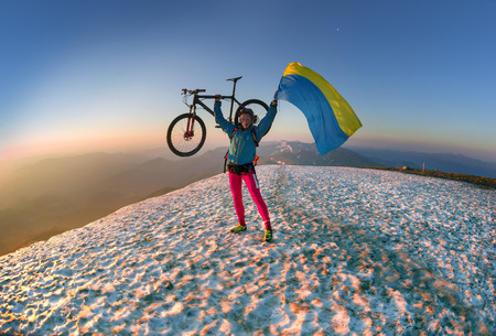 Ukraine, Rakhiv - May 29, 2016: Racer bicycle on top of the highest peaks of the Carpathians Hoverla and Ukraine among the snow against the backdrop of mountain ranges and peaks in the glow of dawn greets the new dayのeditorial素材